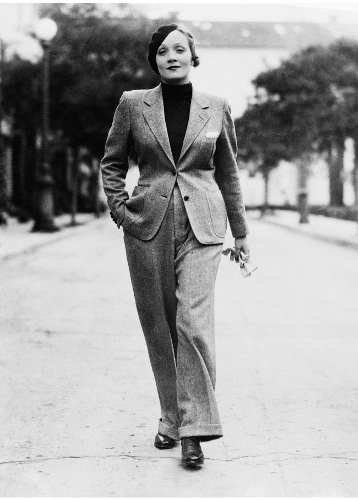 25 Jan 1933 --- Wearing a beret and carrying gloves, Marlene Dietrich, prominent Paramount screen star, jauntily strolls along Hollywood Street attired in a grey man's suit, with turtle-neck sweater. Stylists declare this mode set by Marlene will sweep the country--which probably means that men will have to find themselves some cute tailored skirts. --- Image by © Bettmann/CORBIS
