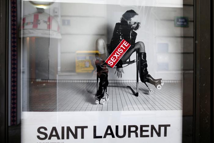A sticker which reads "sexist" is seen on an ad by French fashion house Yves Saint Laurent displayed on a newspaper kiosk in Paris, France, March 6, 2017. France's advertising watchdog on Monday said it had asked French fashion house Yves Saint Laurent to modify two ads from its latest campaign after receiving 50 complaints that they were "degrading" to women. REUTERS/Charles Platiau